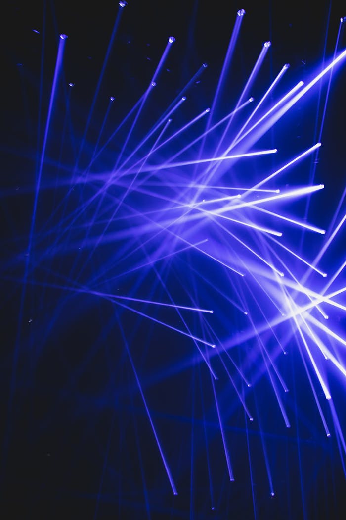 Lightning equipment with abundance of blue beams with white lamps shining on ceiling in darkness during light performance in modern studio